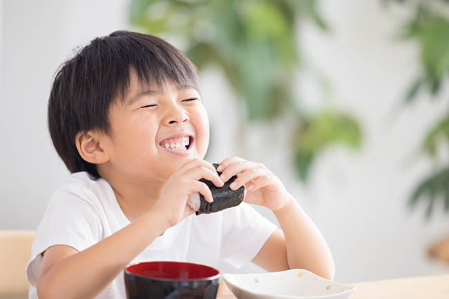 美味しそうにおにぎりを食べている子ども